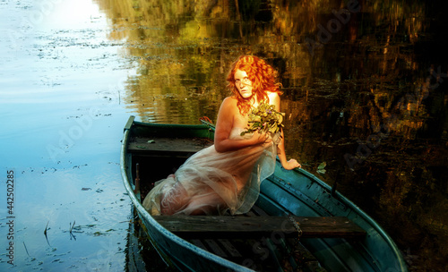 Картината върху платно sensual, seductive, young sexy red-haired woman sits in a boat like a siren in a