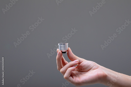 Close up of caucasian businesswoman holding base of light bulb, isolated on grey background