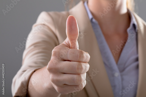 Midsection of caucasian businesswoman touching virtual interface on grey background