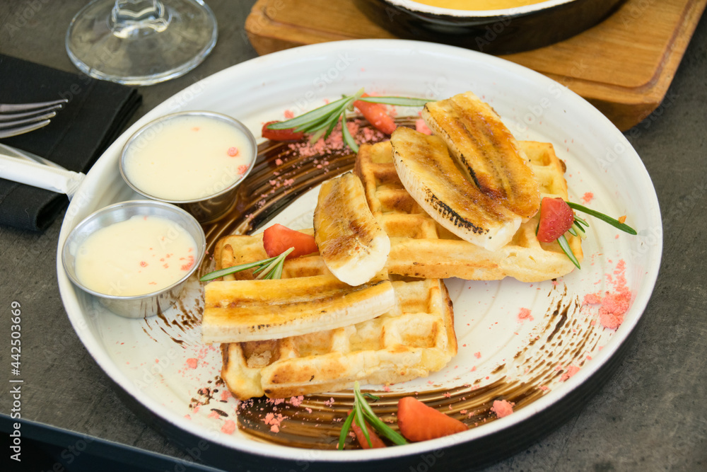 Viennese waffles with chocolate, strawberries and sauce on a white restaurant plate Viennese waffles with chocolate, strawberries and sauce on a white restaurant plate