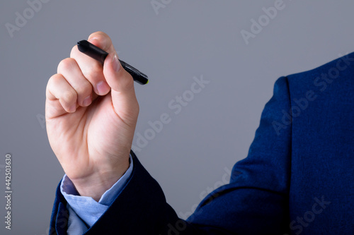 Midsection of caucasian businessman holding marker, isolated on grey background