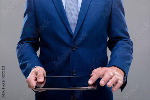 Midsection of caucasian businessman using tablet, isolated on grey background