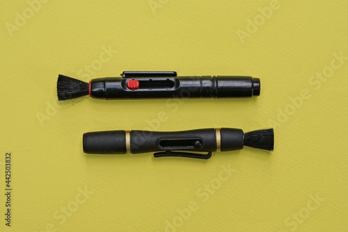 two black long cleaning pencils lies on a yellow table