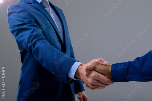 Caucasian and african american business people shaking hands, isolated on grey background