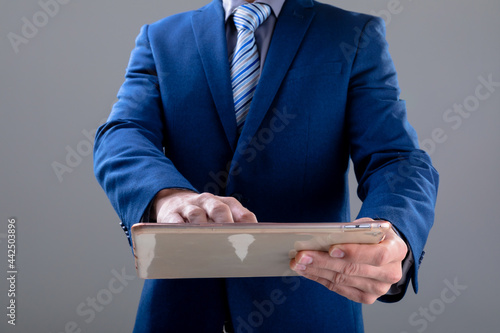 Midsection of caucasian businessman using tablet, isolated on grey background photo