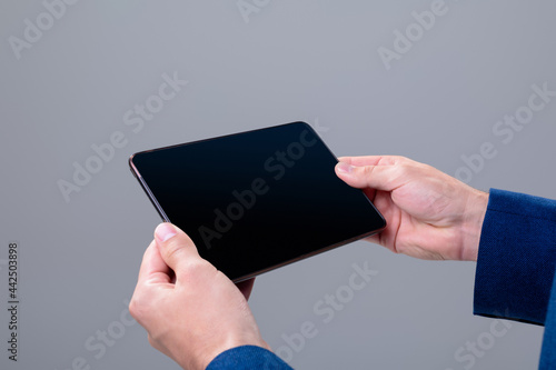 Midsection of caucasian businessman using tablet, isolated on grey background photo