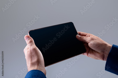 Midsection of caucasian businessman using tablet, isolated on grey background photo