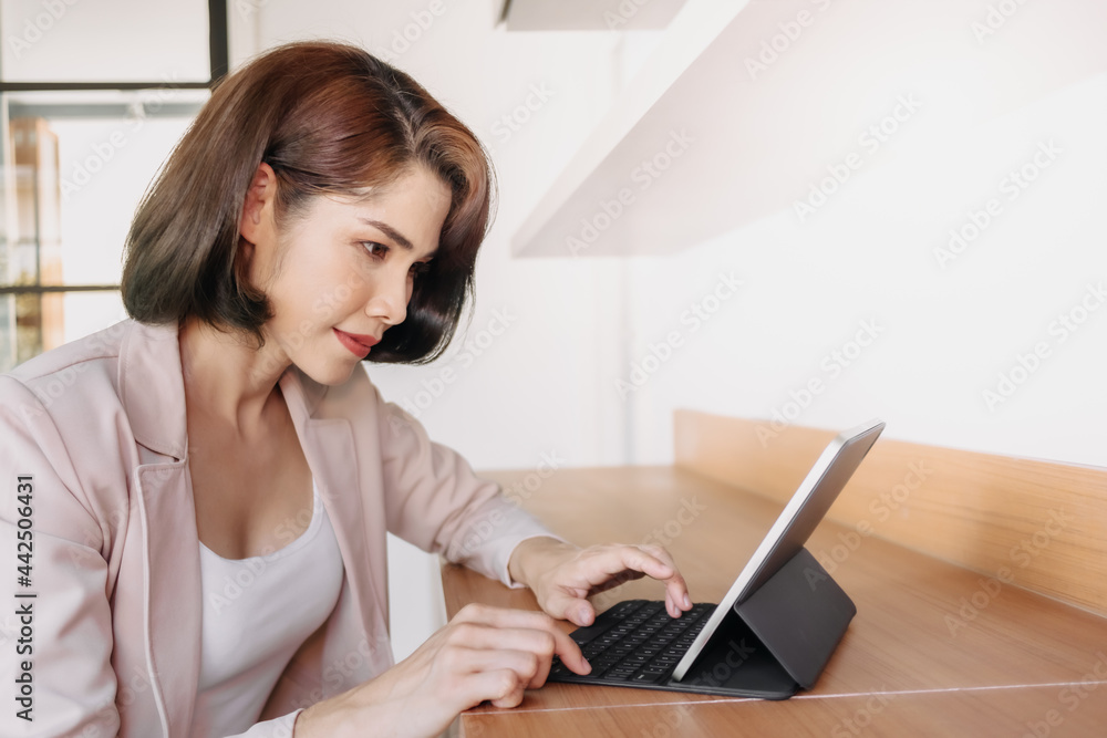 Happy Asian working woman is using a tablet in the office. Happy Asian working woman is using a tablet in the office.