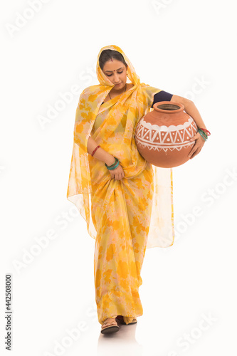 A woman holding a matki by her waist looking downwards. photo