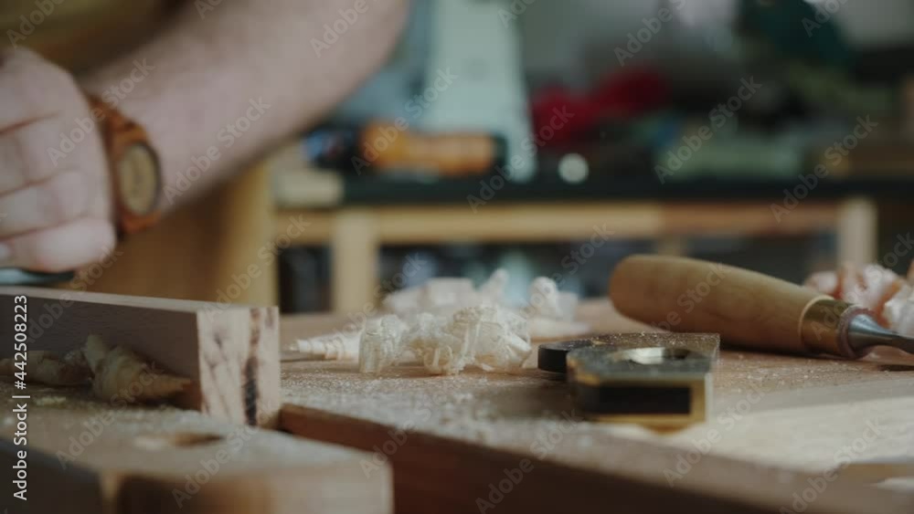 A carpenter planes a blank wooden board with a plane in a workshop. A carpenter planes a blank wooden board with a plane in a workshop.