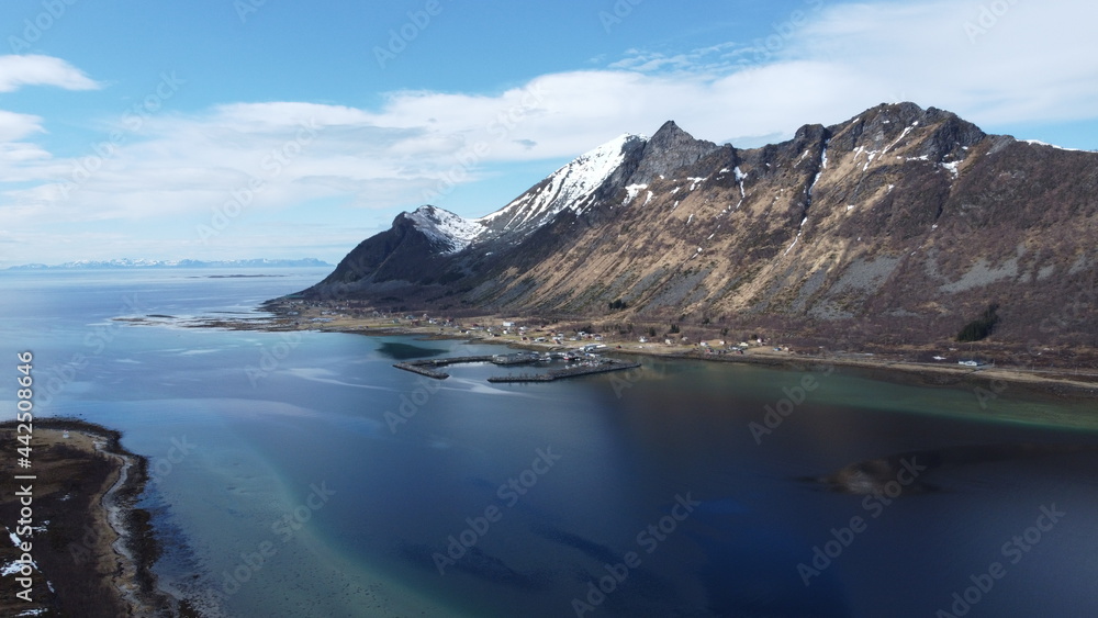majestic blue fjord surrounded by mighty mountains on the island of senja in the small fishing village of Grunnfarnes, northern Norway in summer, aerial shot
