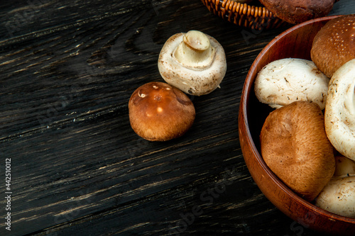 side view of fresh mushrooms in a bowl on dark wooden background with copy space