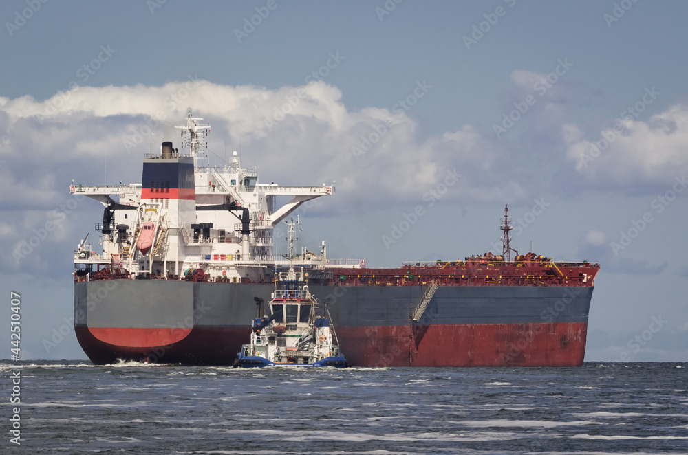 BULK CARRIER - The ship sails from port to sea secured by tug
