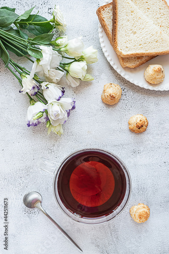 Top view of a breakfast with a cup of tea, cookies, bread and flowers