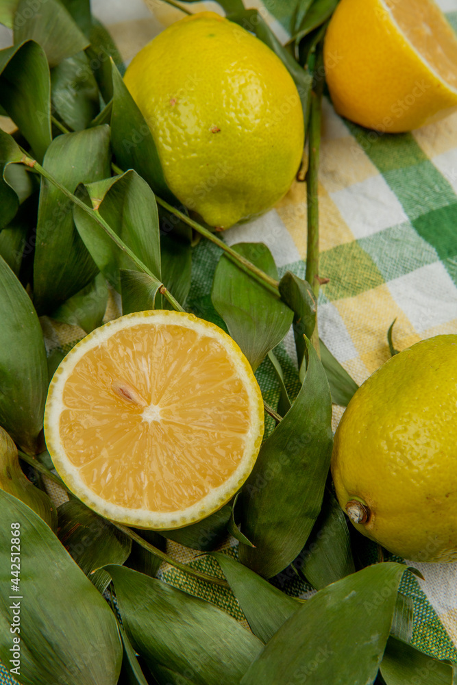 side view of fresh ripe lemons with green leaves on plaid fabric background