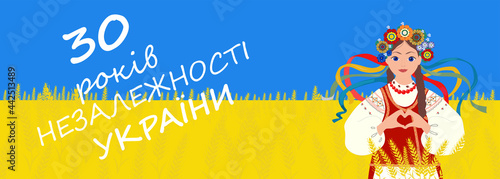 Happy Ukrainian girl dressed in vyshyvanka making heart sign with hands. Sky and wheat field is colors of the national flag - yellow and blue. Celebrate 30 years of Independence Day of Ukraine