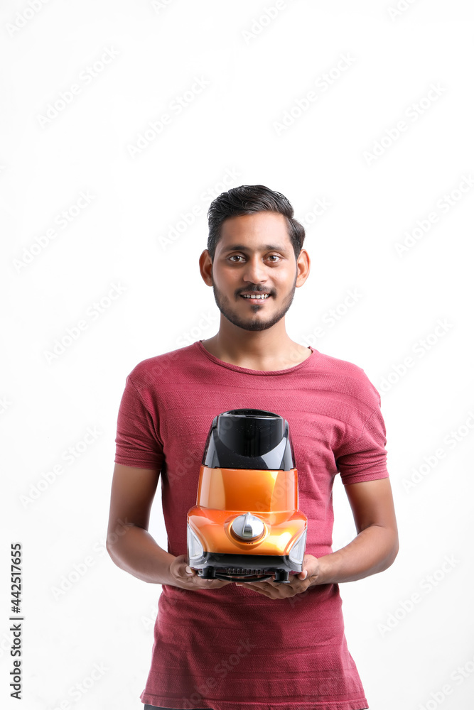 Young indian man holding electronic mixer in hand over white background. Young indian man holding electronic mixer in hand over white background.