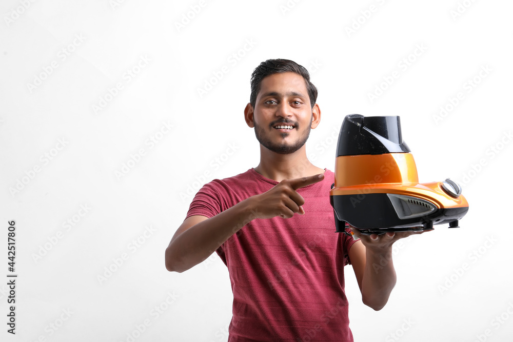 Young indian man holding electronic mixer in hand over white background. Young indian man holding electronic mixer in hand over white background.