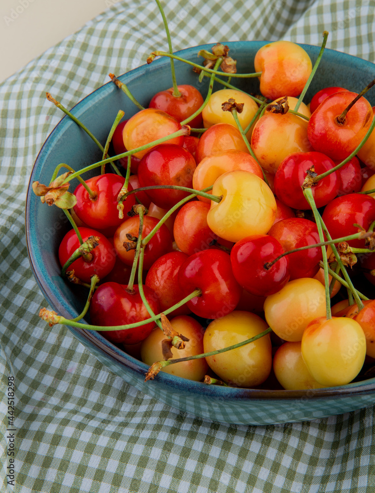 side view of ripe rainier cherries in a bowl on plaid fabric background side view of ripe rainier cherries in a bowl on plaid fabric background