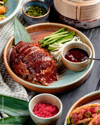 side view of traditional asian food peking duck with cucumbers and sauce on a plate photo
