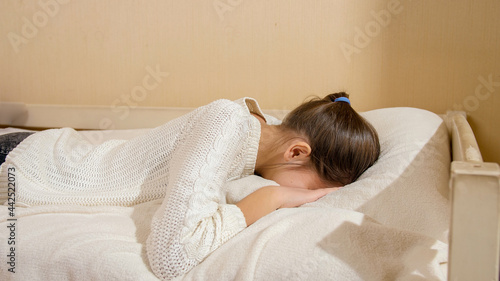 Beautiful teenage girl jumping on bed and crying in pillow. Teenager depression and social problems