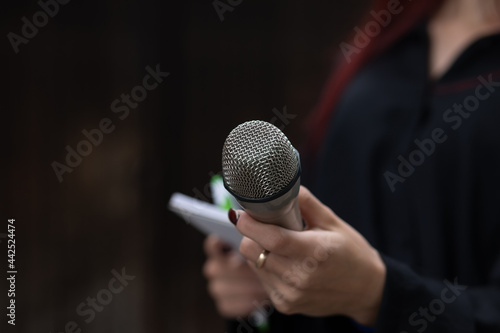 Journalist in action at news conference, holding microphones and writing notes