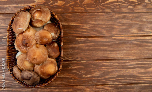 top view of fresh mushrooms in a wicker basket on wooden rustic background with copy space