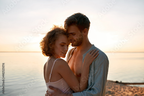 Beautiful young caucasian lovers hugging at sunset