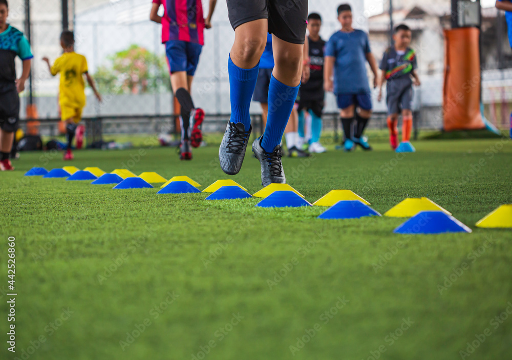 Obraz premium Soccer ball tactics on grass field with barrier for training children jump skill
