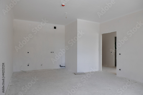 construction of a residential building. The interior of the apartment without finishing in gray tones. Concrete floor.