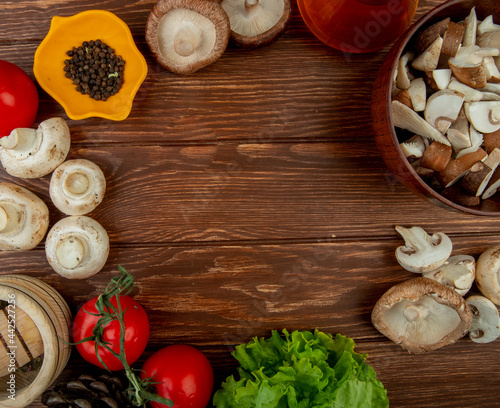top view of fresh mushrooms with black peppercorns fresh tomatoes wooden mortar with dried herbs and a bowl with sliced mushrooms on rustic wooden background with copy space