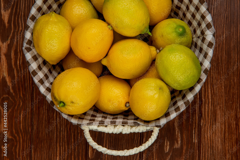 top view of fresh ripe lemons in a wicker basket on wooden background