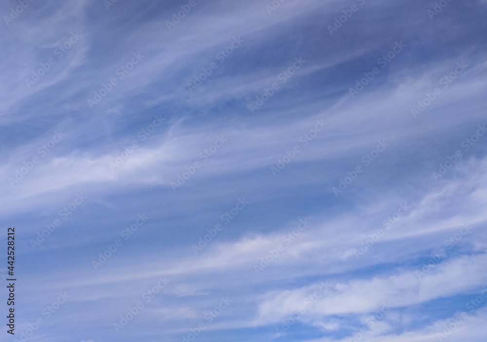 Blue sky with stripped clouds. Long transparent cloudscape. Sunny summer day background. Psychological peace of mind concept. Season changes weather forecast.