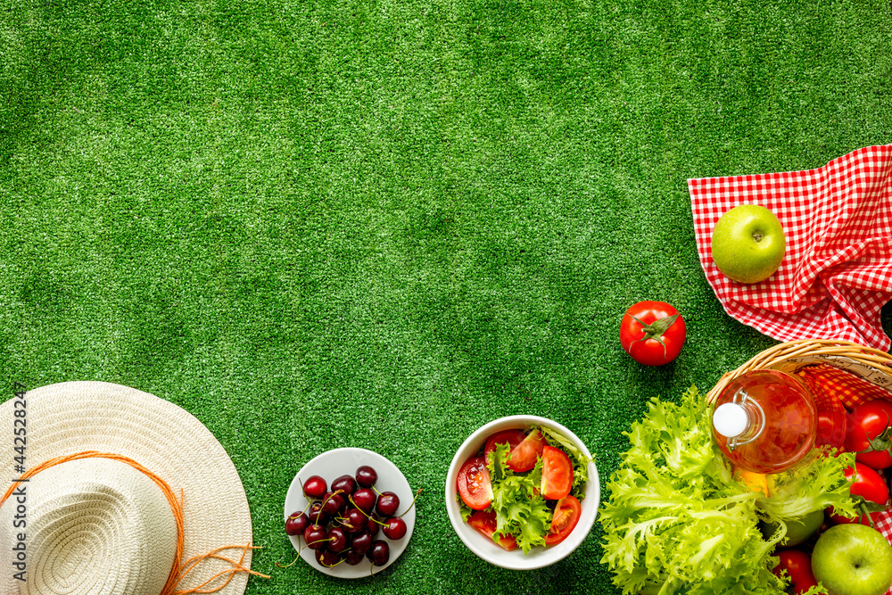 Naklejka premium Summer picnic setting. Basket with food on red cloth, top view