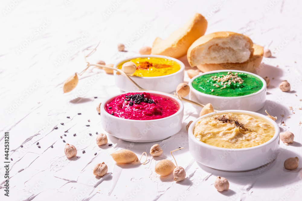 Various hummus dips, the flat lay of hummus in different colors with spinach, beetroot, turmeric and vegetables Various hummus dips, the flat lay of hummus in different colors with spinach, beetroot, turmeric and vegetables