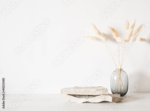 Grey natural stones podium on white background, platform for product display and dry branches in vase