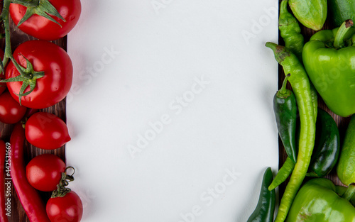 top view of fresh vegetables ripe tomatoes red and green chili peppers cucumbers and green bell peppers on rustic background