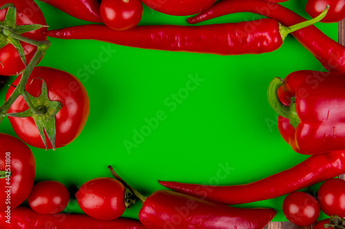 top view of fresh vegetables ripe tomatoes with red chili peppers on green background with copy space