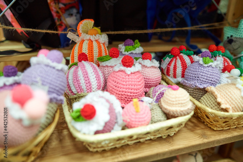 Knitted cupcakes of different colors on a store shelf