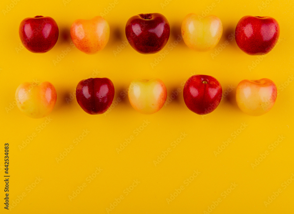 top view of ripe red and yellow cherries isolated on yellow background with copy space top view of ripe red and yellow cherries isolated on yellow background with copy space