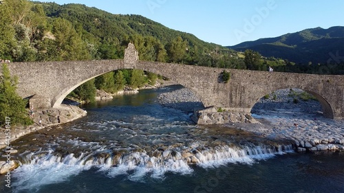 Europe, Italy , Bobbio , Piacenza - Drone aerial view of roman historic stones bridge Ponte Gobbo o Ponte Vecchio pass over the river Val Trebbia