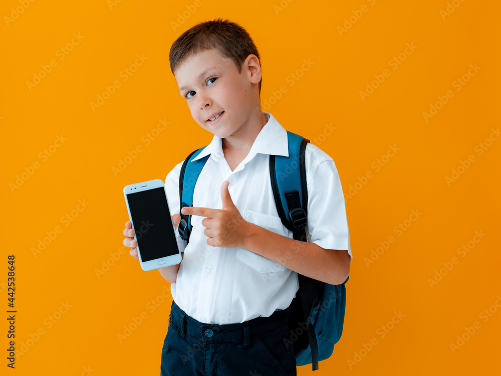 schoolchild boy holds mobile phone isolated yellow background. Smartphone close up with black display.