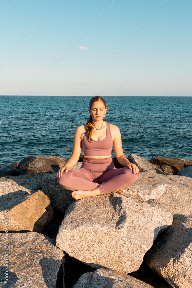 Woman practicing yoga in Lotus pose on beach Woman practicing yoga in Lotus pose on beach