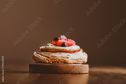 Torta Pavlova sobre textura madera. torta con iluminación lateral