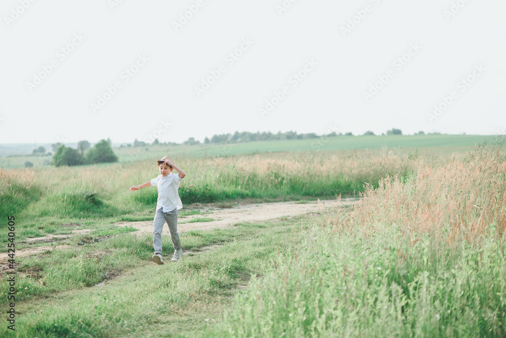 Happy boy running on green grass against sky. Soft focus. Summer activities