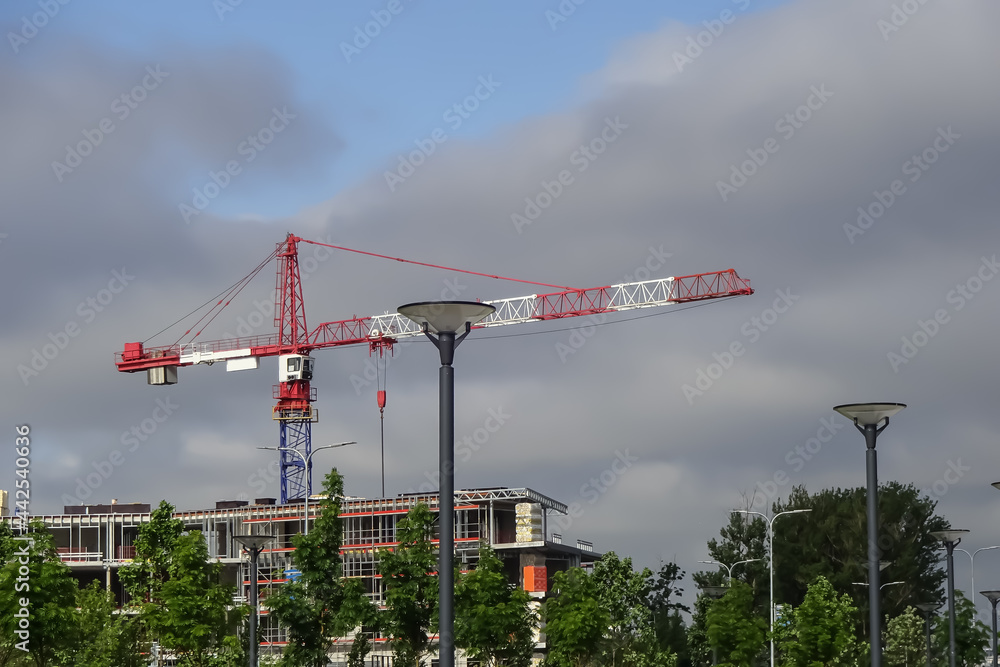 Red and white tower crane. New apartments building construction. Cloudy grey sky on a summer day. Reidi street, Tallinn, Estonia Red and white tower crane. New apartments building construction. Cloudy grey sky on a summer day. Reidi street, Tallinn, Estonia