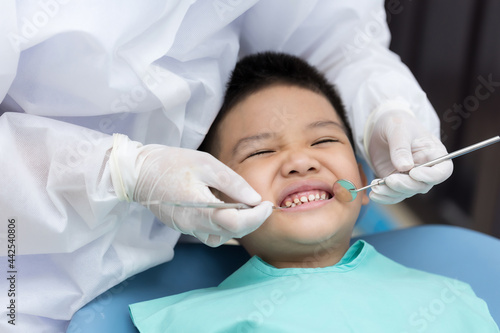 Dentist examining Asian little boy teeth in clinic.