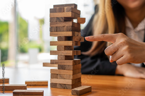 A businesswoman pulls a wooden block in the middle of the floor. It is like managing business risks with strategies. and project management the best of the business