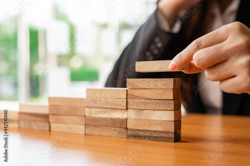 ..A businesswoman puts a wooden block at the highest point. It is like reaching the highest point in business with strategy. and the beginning project management the best of the business