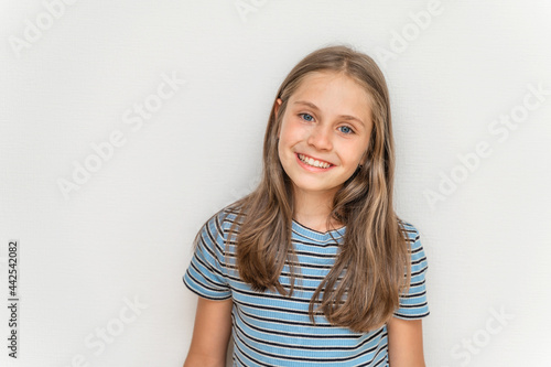 Portrait of a smiling little girl child with long blonde hair on a white background